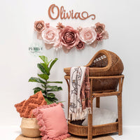 Blush pink,dusty rose wall paper flowers in nursery above rattan crib
